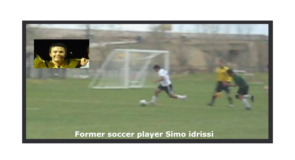 Soccer player (Simo Idrissi) in white tshirt and black short dribbling forward on a grassy field, infront of him exactly to his right foot a soccer ball, chased by a player in green tshirt and black short, on the line a referee with a yellow tshirt and black short with goalpost outside the field.