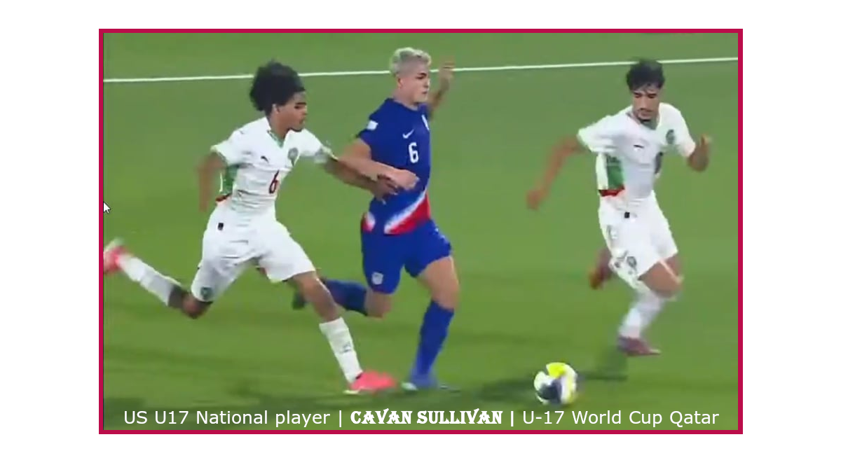 Cavan Sullivan of the United States controls the ball during a U-17 World Cup Qatar match, flanked by El Mahdi Saidi and Hamza Bouhaddi of Morocco. Sullivan wears a blue USSF kit, while the Moroccan players wear white. All three are in motion on a green field, capturing a moment of midfield pressure and tactical intensity.