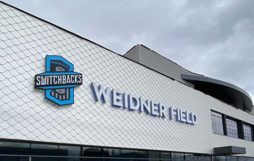 Colorado Springs Switchbacks Split with Coach James Chambers. This image of Weidner Field, home of the Colorado Springs Switchbacks FC, visually anchors the story of the club’s recent split with head coach James Chambers. The stadium’s modern design and prominent team branding reflect the professional stature of the organization, while the overcast sky adds a subdued tone—mirroring the uncertainty or transition that often accompanies a coaching change.
